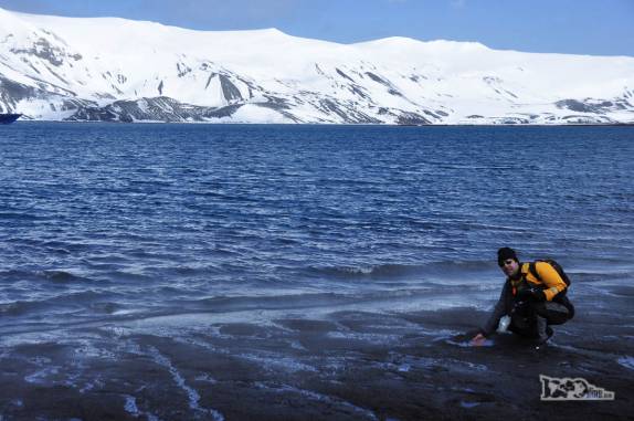 Esquentando as mãos nas águas quentes que brotam nas areias da praia de Deception Island, na Antártida